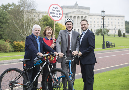 Politicians and Sustrans staff with bike and campaign sign with Stormont building in background
